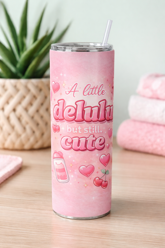 Pink tumbler with decorative text and graphics on a wooden surface.